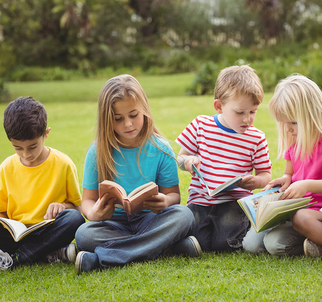 4 kids reading books on the field